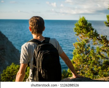 back view of man with backpack standint on the mountain in front of mountain