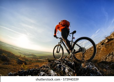 back view of a man with a bicycle and red backpack against the blue sky. cyclist rides a bicycle. Rear view people collection. backside view of person. blue sky background and mound.