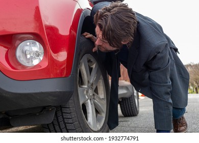 Back View Of A Man Crouching Down And Looking Into A Car