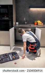 Back View Of Man Crouching Near Kitchen Sink