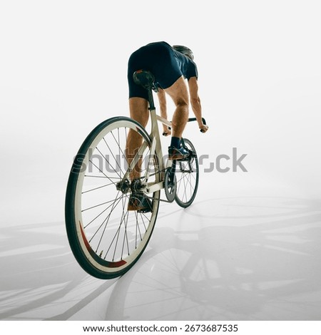 Back view of man, cyclist in motion, training, riding bicycle with determination and focus isolated on white background. Concept of sport, competition, active lifestyle, endurance