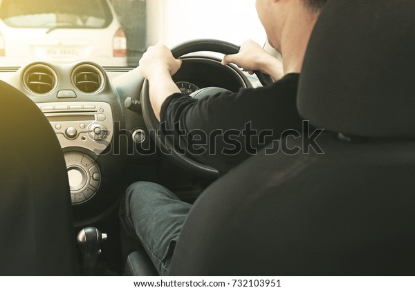 Back view of man driving\
a city car.