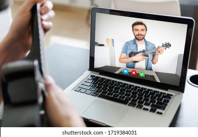 Back View Of Man Follow A Guitar Course In Video Conference. Man Using Laptop For A Online Music Lesson In Video Call.