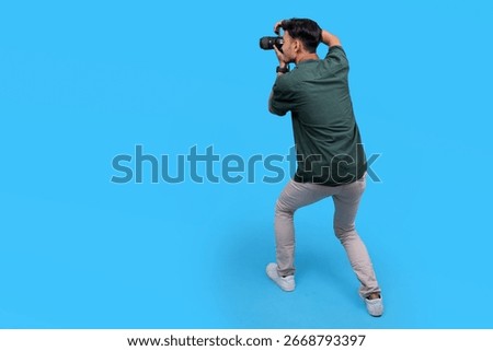 Back View of Man Holding The Camera and Take Photo to Empty Side Isolated On Blue Background