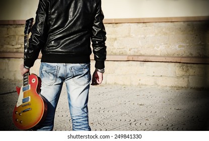 Back View Of A Man Holding A Guitar 