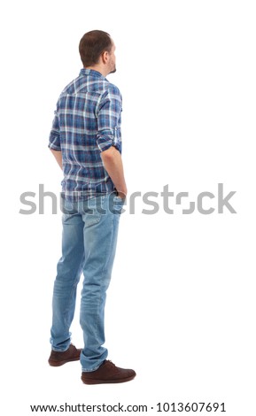 Back view of man in jeans. Standing young guy. Rear view people collection.  backside view of person.  Isolated over white background. A man in a blue shirt stands by putting his hands in his pockets