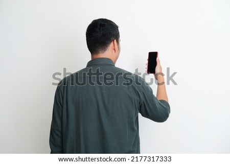 Back view of a man looking to the mobile phone that he hold