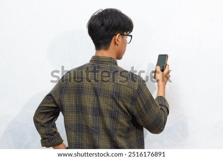 Back view of a man looking to the mobile phone that he hold