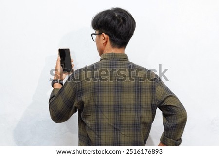Back view of a man looking to the mobile phone that he hold