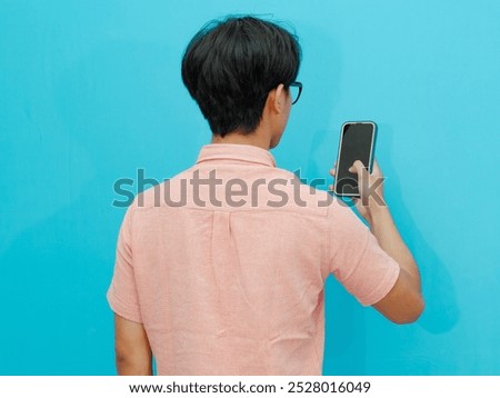 Back view of a man looking to the mobile phone that he hold