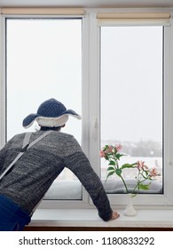 Back view of man looking in window on snow covered city