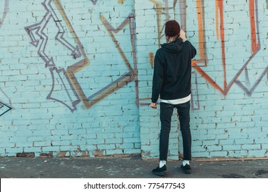 back view of man painting colorful graffiti on wall