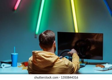 Back View Of Man Playing Video Game With Steering Wheel