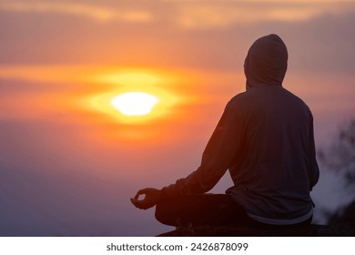 Back view of man is relaxingly practicing meditation yoga mudra at mountain top with sunrise during winter to attain happiness from inner peace wisdom for healthy mind and soul