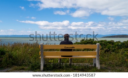 Back view of a man sitting alone on a bench and admiring the view on the estuary at Kamouraska, Canada
