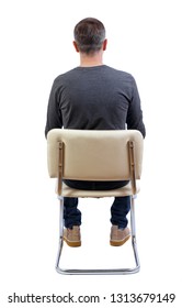 Back View Of A Man Sitting On A Chair. Rear View People Collection.  Backside View Of Person.  Isolated Over White Background. A Man In A Gray Jacket Sits On A White Chair And Looks Ahead.