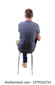 Back View Of A Man Sitting On A Chair. Rear View People Collection.  Backside View Of Person.  Isolated Over White Background. The Man Is Sitting Cross-legged On A Stool.