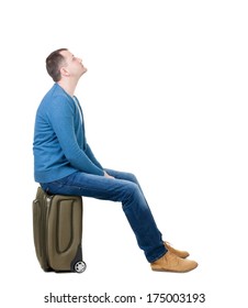 Back View Man Sitting On Suitcase. Waiting At The Station. Backside View Person.  Rear View People Collection. Isolated Over White Background. Guy With Travel Bag On Wheels Looking At Something At Top