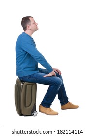 Back View Man Sitting On A Suitcase. Waiting At The Station. Backside View Of Person.  Rear View People Collection. Isolated Over White Background. Guy With Travel Bag On Wheels Looking At Something 