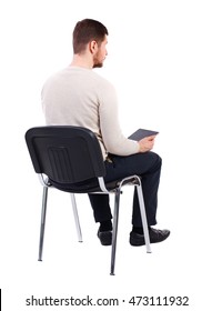 Back View Of Man Sitting On Chair And Looks At The Screen Of The Tablet.  Businessman Watching. Rear View People Collection.  Backside View Of Person.  Isolated Over White Background. The Bearded Man