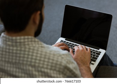 Back View Of Man Sitting On Couch And Using Laptop