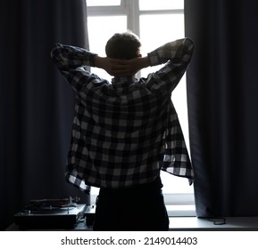 back view of man standing in front of the window in the morning at home, silhouette