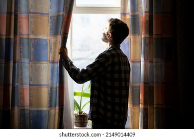 back view of man standing in front of the window in the morning at home, silhouette
