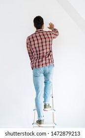 Back View Of Man Standing At Ladder And Looking At Wall Isolated On White