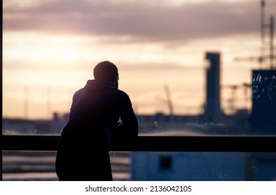 Back view of a man standing and looking through glass window of the airport building to outside. Thinking man. Rear view of a man wear protective face mask waiting for the flight. Travel alone. - Powered by Shutterstock