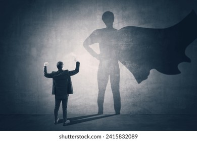 Back view of man standing on concrete wall background with cape shadow. Leadership, success and power concept - Powered by Shutterstock