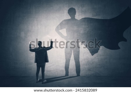 Back view of man standing on concrete wall background with cape shadow. Leadership, success and power concept