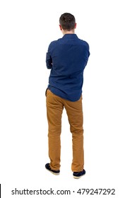 Back view of man . Standing young guy. man in a blue shirt with the sleeves rolled up, standing with her hands folded on his chest.