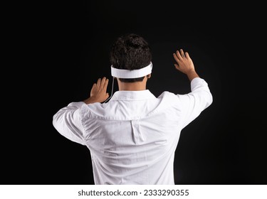 Back view of man touching invisible screen while experiencing cyberspace in vision pro VR glasses, standing on black studio background - Powered by Shutterstock