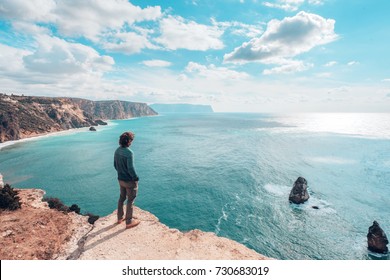 Back view of man traveler standing on mountain alone and looking at autumn sea landscape. Hiking in cold season. Wanderlust concept scene. - Powered by Shutterstock