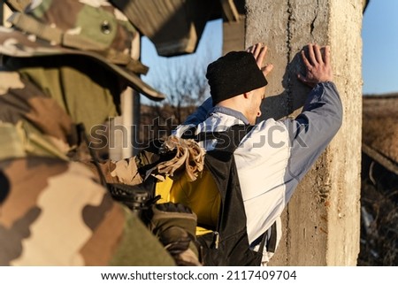 Back view of man in uniform unknown military soldier or special forces police arresting and searching criminal illegal migrant or terrorist in sunny day