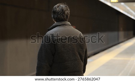 Back view of a man waiting on the metro station platform.Passenger standing alone in underground train station.