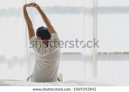 Back of view man wake up and stretching on bed in bedroom in the morning.at home in holiday.