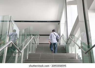 Back View Of Man Walking Up The Stairs Inside A Subway Building. Commuter Travel To Work Concept.