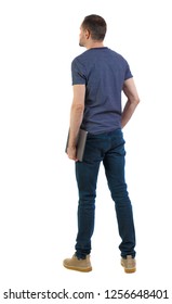 Back View Of A Man Who Is Standing With A Laptop. Rear View People Collection.  Backside View Of Person.  Isolated Over White Background. A Student Is Thoughtfully Holding A Laptop In His Hand