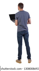 Back View Of A Man Who Is Standing With A Laptop. Rear View People Collection.  Backside View Of Person.  Isolated Over White Background. A Young Professional Checks The Information In A Laptop.