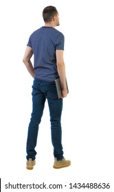 Back View Of A Man Who Is Standing With A Laptop. Rear View People Collection. The Guy In The Shoes Holding A Laptop Under His Arm. Backside View Of Person. Isolated Over White Background.