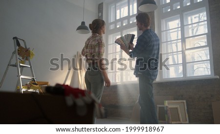 Back view of man and woman discussing decorate details in new house. Young family choosing pastel color for apartment walls indoors. Happy couple speaking about home repair questions inside.