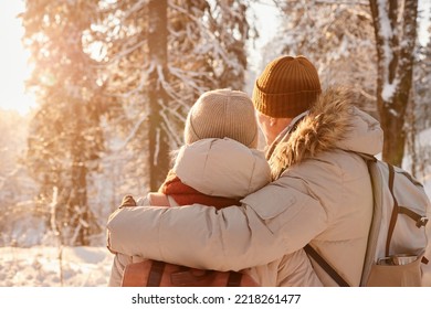 Back view of mature couple embracing in winter forest lit by sunlight, copy space - Powered by Shutterstock