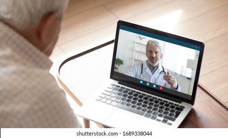 Back view of mature man have video call consultation with male doctor using laptop Webcam, close up of elderly male patient talk speak with GP or physician at home, discuss illness, consult online - Powered by Shutterstock