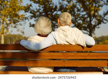 Back view of mature senior couple family sitting on the bench in park and hugging enjoying retirement and spending time together in nature. Elderly people love, care and relationship concept. - Powered by Shutterstock