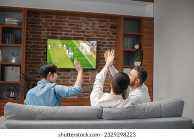 Back view of men watching a football game on tv and sitting on a sofa - Powered by Shutterstock