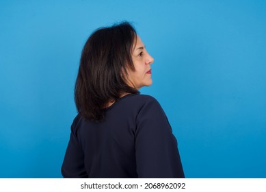 The Back View Of Middle Aged Arab Woman Standing Against Blue Background Studio Shoot.