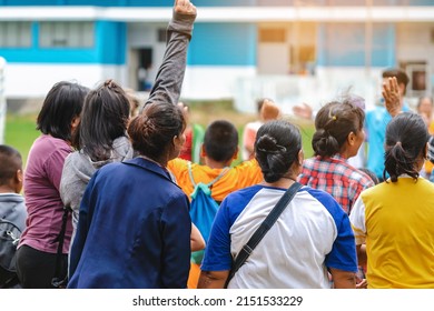 Back View Of Moms Watch And Cheering Their Sons Playing Football In School Tournament On Sideline. Sport, Outdoor Active,  Spectator Watching Soccer Game. Parents Care And Encourage Their Children.