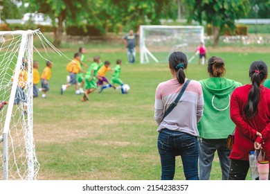 Back view of Moms watch and cheering their sons playing football in school tournament on sideline. Sport, outdoor active,  Spectator watching soccer game. Parents care and encourage their children. - Shutterstock ID 2154238357