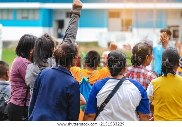 Back view of Moms watch and cheering their sons\
playing football in school tournament on sideline. Sport, outdoor\
active,  Spectator watching soccer game. Parents care and encourage\
their children.